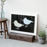 Artprint Take-off auf einer Holzbohle stehend, mit Pflanze und Holzhocker daneben.